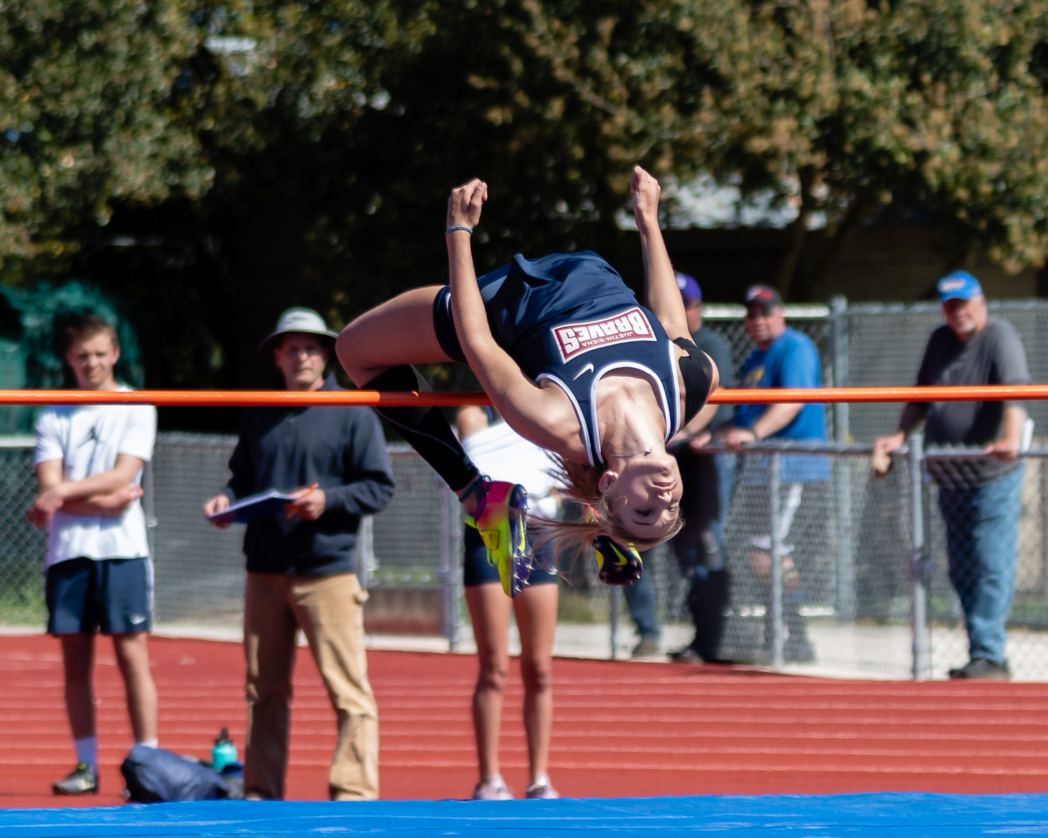 Athlete prepares for pole vault on a track with others watching.
