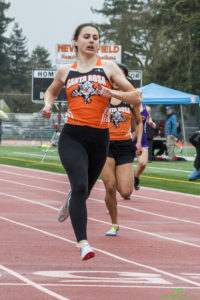 Athlete prepares for pole vault on a track with others watching.