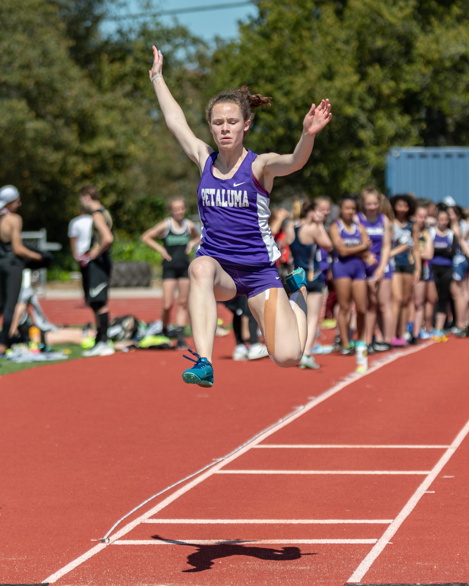 Athlete prepares for pole vault on a track with others watching.