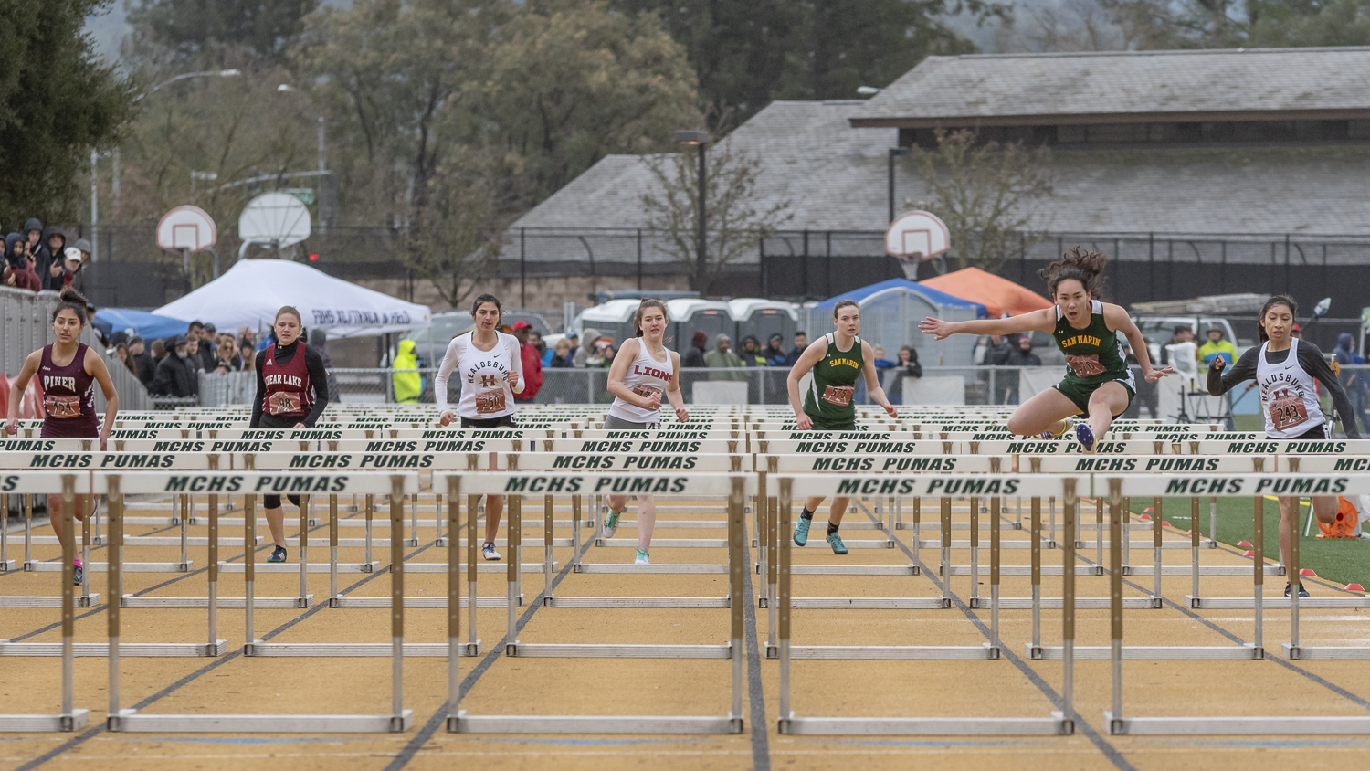 Athlete prepares for pole vault on a track with others watching.