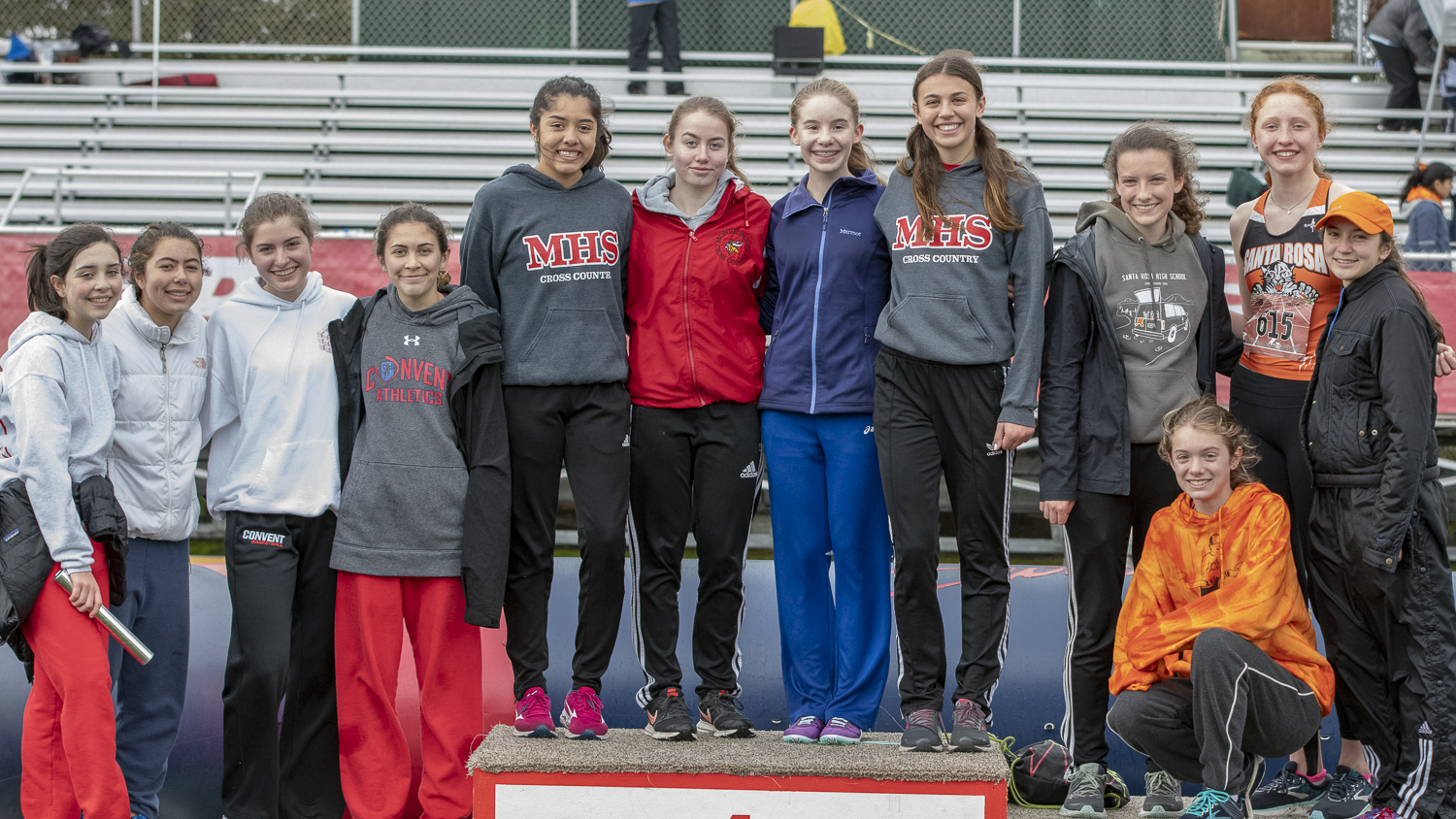 Athlete prepares for pole vault on a track with others watching.
