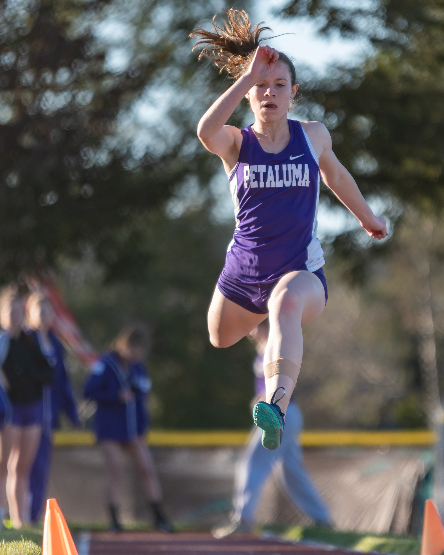 Athlete prepares for pole vault on a track with others watching.
