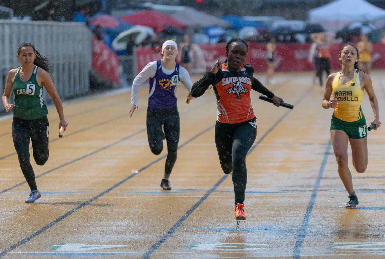 Athlete prepares for pole vault on a track with others watching.