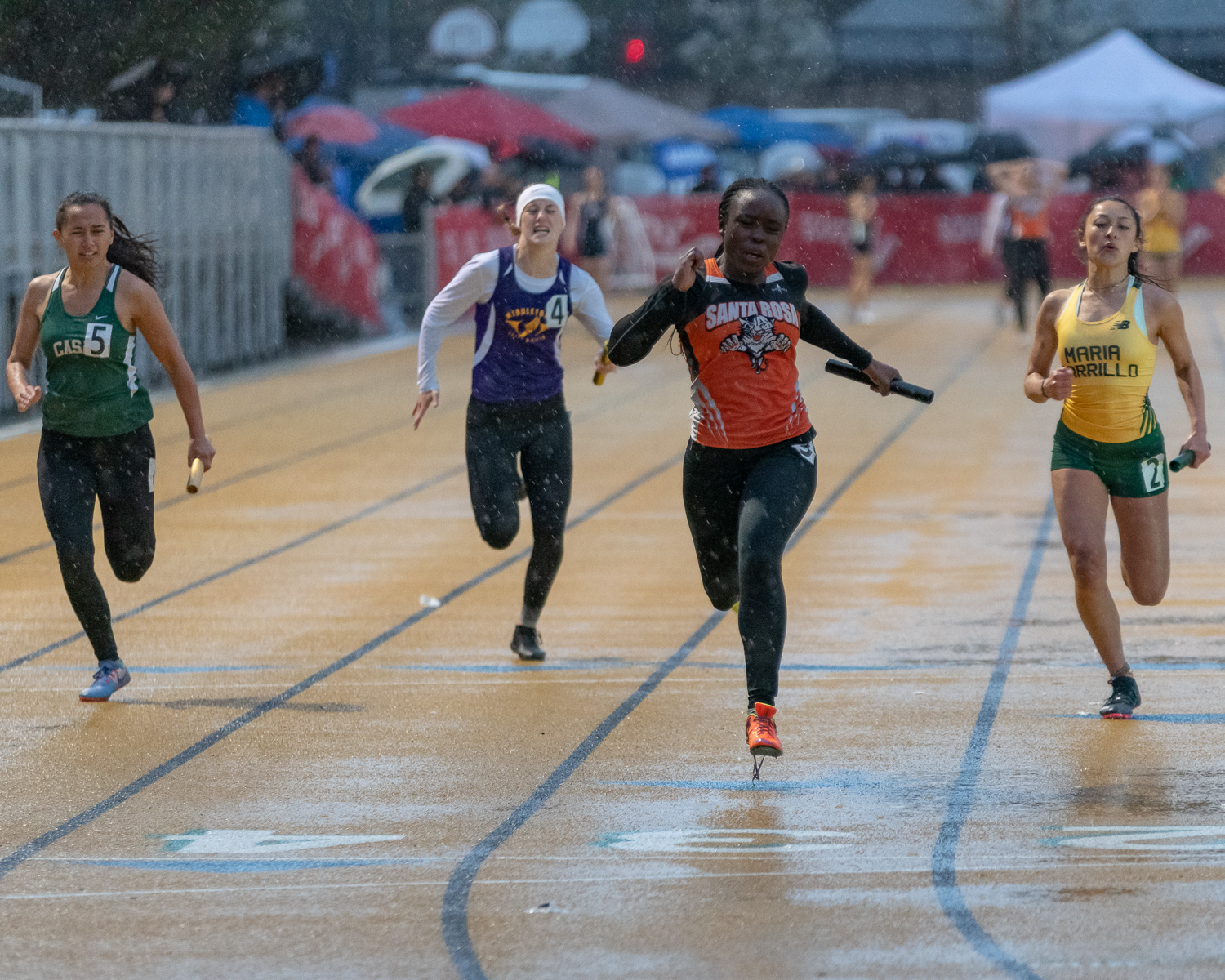 Athlete prepares for pole vault on a track with others watching.