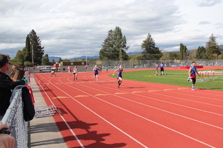 Athlete prepares for pole vault on a track with others watching.