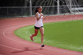Athlete prepares for pole vault on a track with others watching.