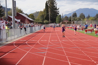 Athlete prepares for pole vault on a track with others watching.