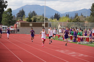 Athlete prepares for pole vault on a track with others watching.