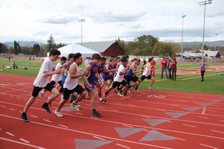 Athlete prepares for pole vault on a track with others watching.