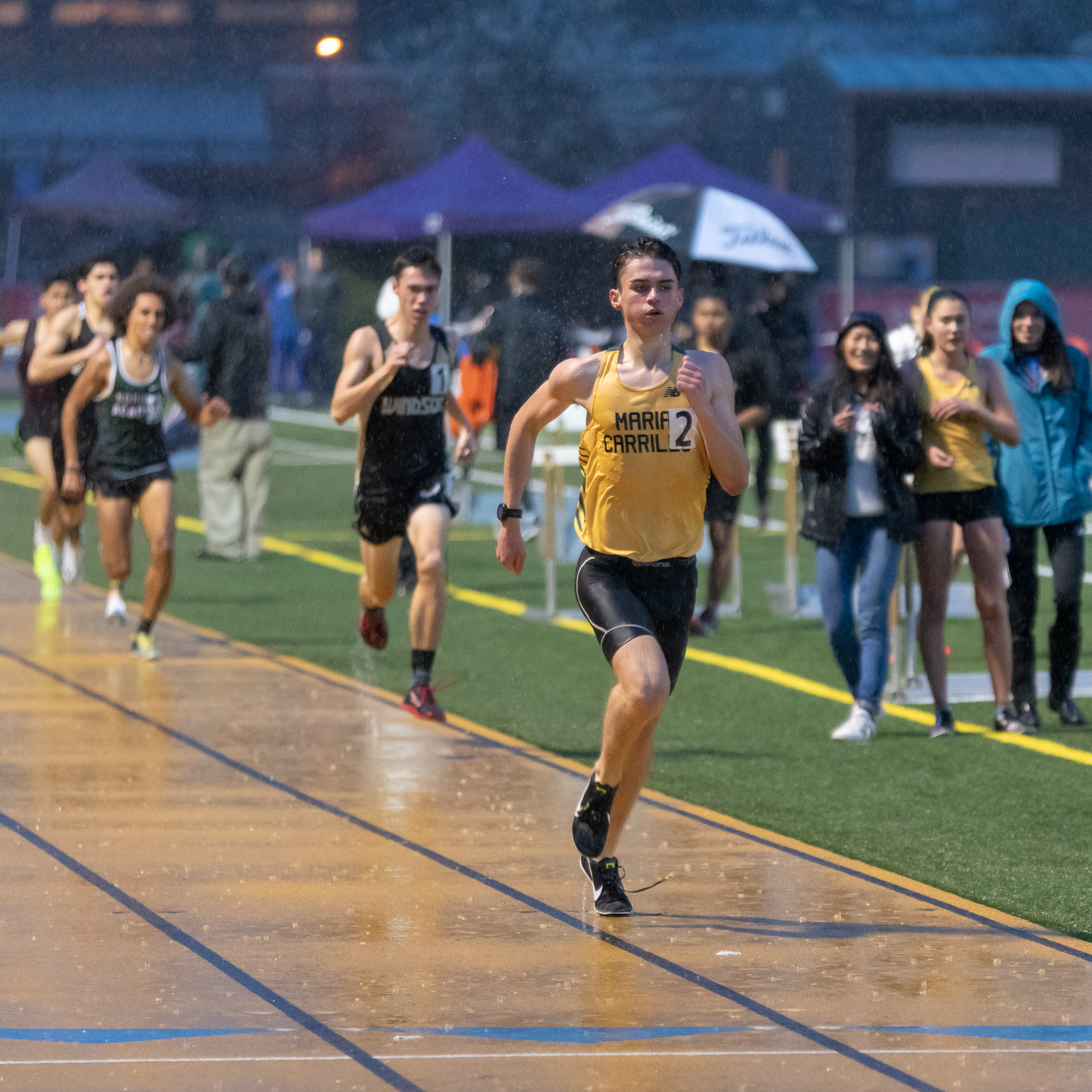 Athlete prepares for pole vault on a track with others watching.