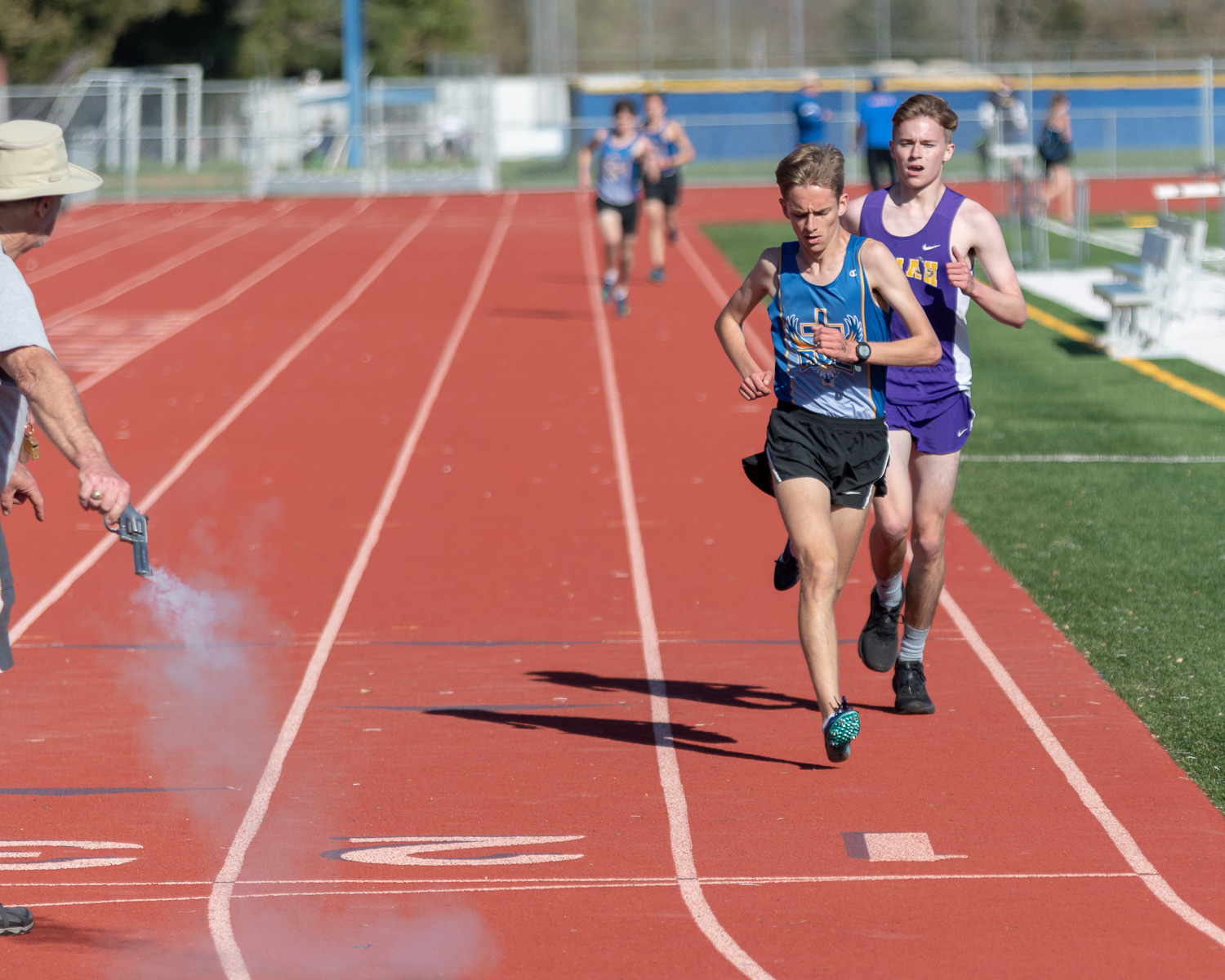 Athlete prepares for pole vault on a track with others watching.