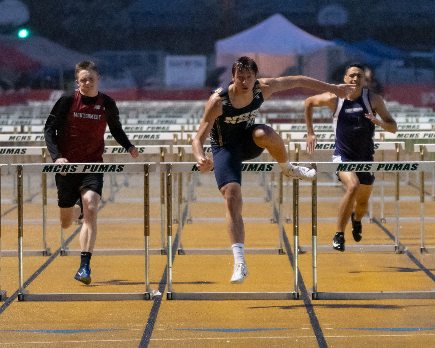 Athlete prepares for pole vault on a track with others watching.