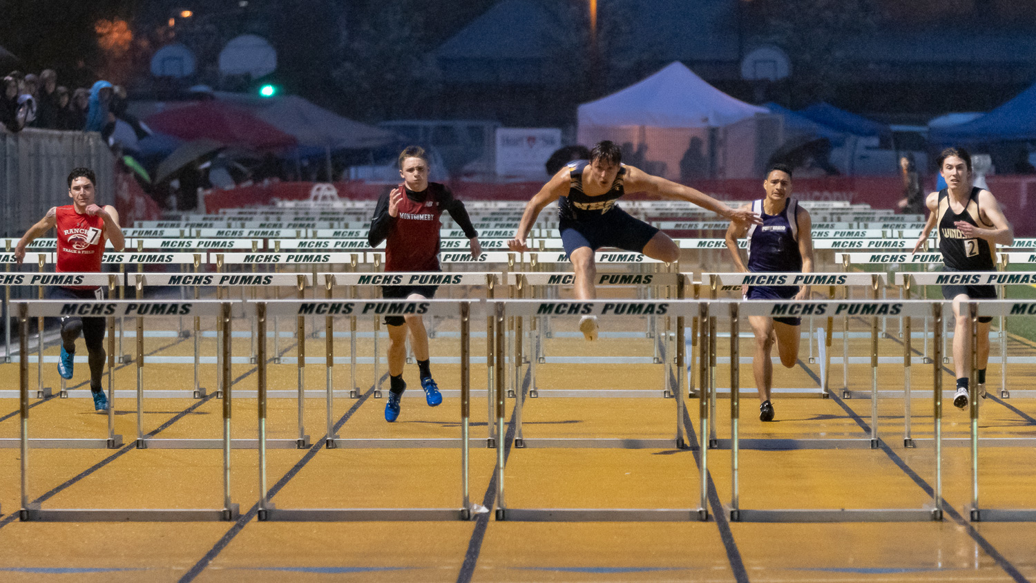 Athlete prepares for pole vault on a track with others watching.