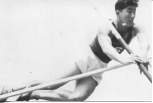 Athlete prepares for pole vault on a track with others watching.