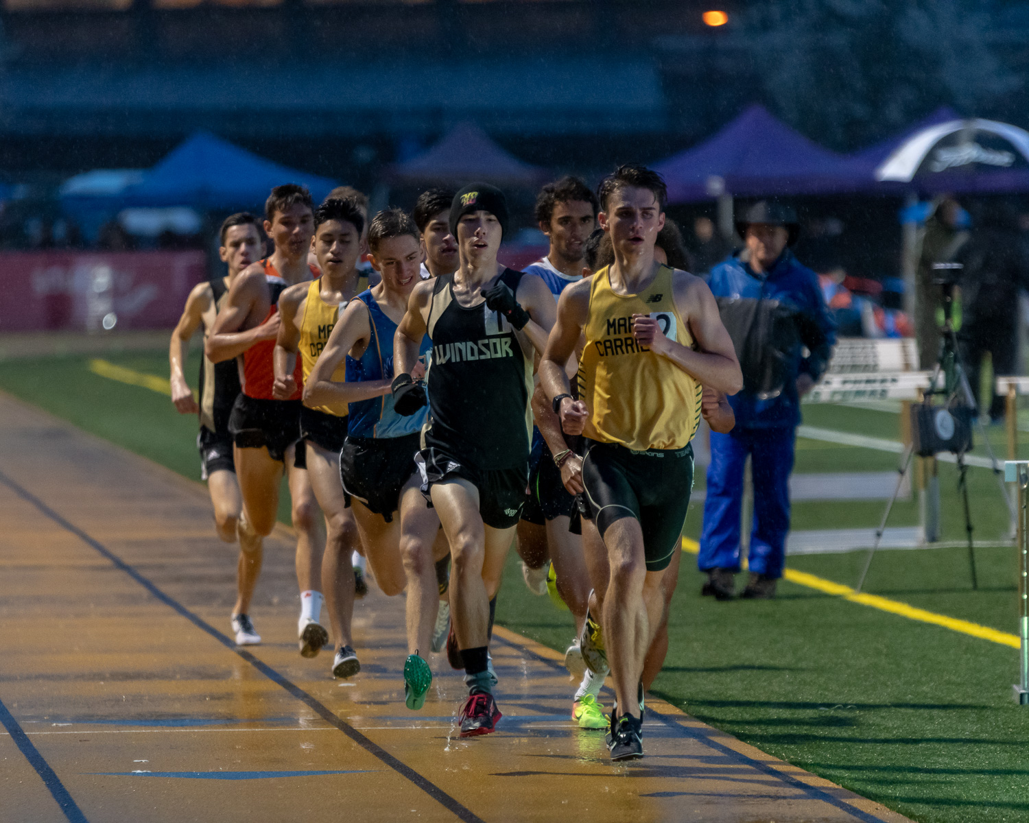 Athlete prepares for pole vault on a track with others watching.