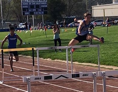 Athlete prepares for pole vault on a track with others watching.