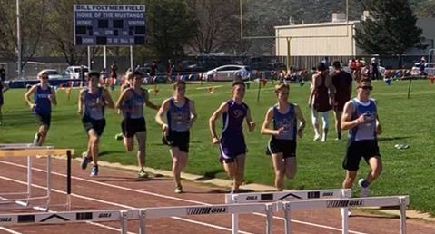 Athlete prepares for pole vault on a track with others watching.
