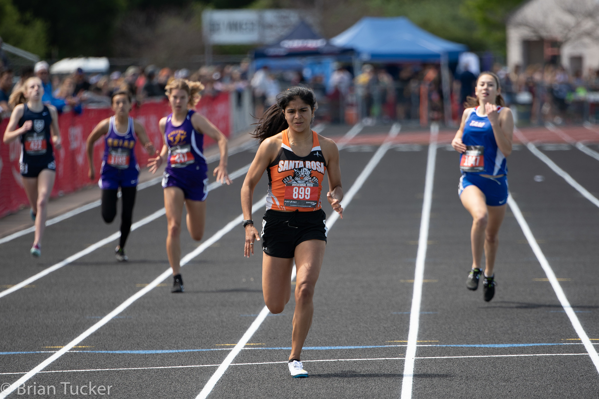 Athlete prepares for pole vault on a track with others watching.