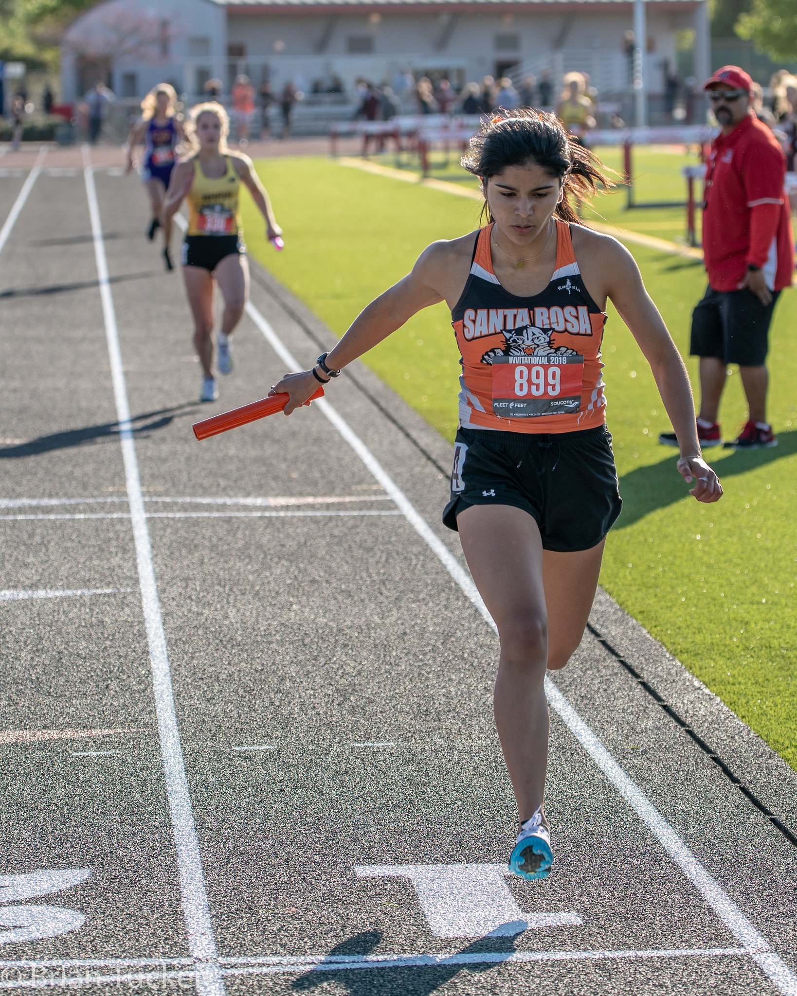 Athlete prepares for pole vault on a track with others watching.