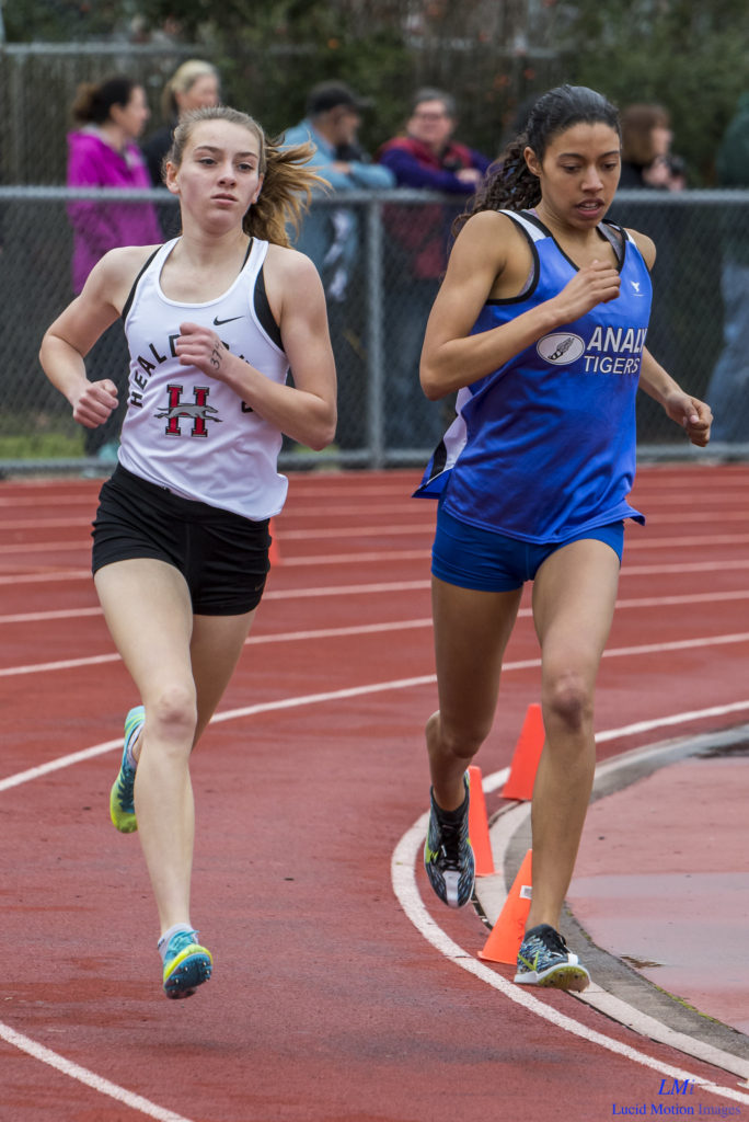Athlete prepares for pole vault on a track with others watching.