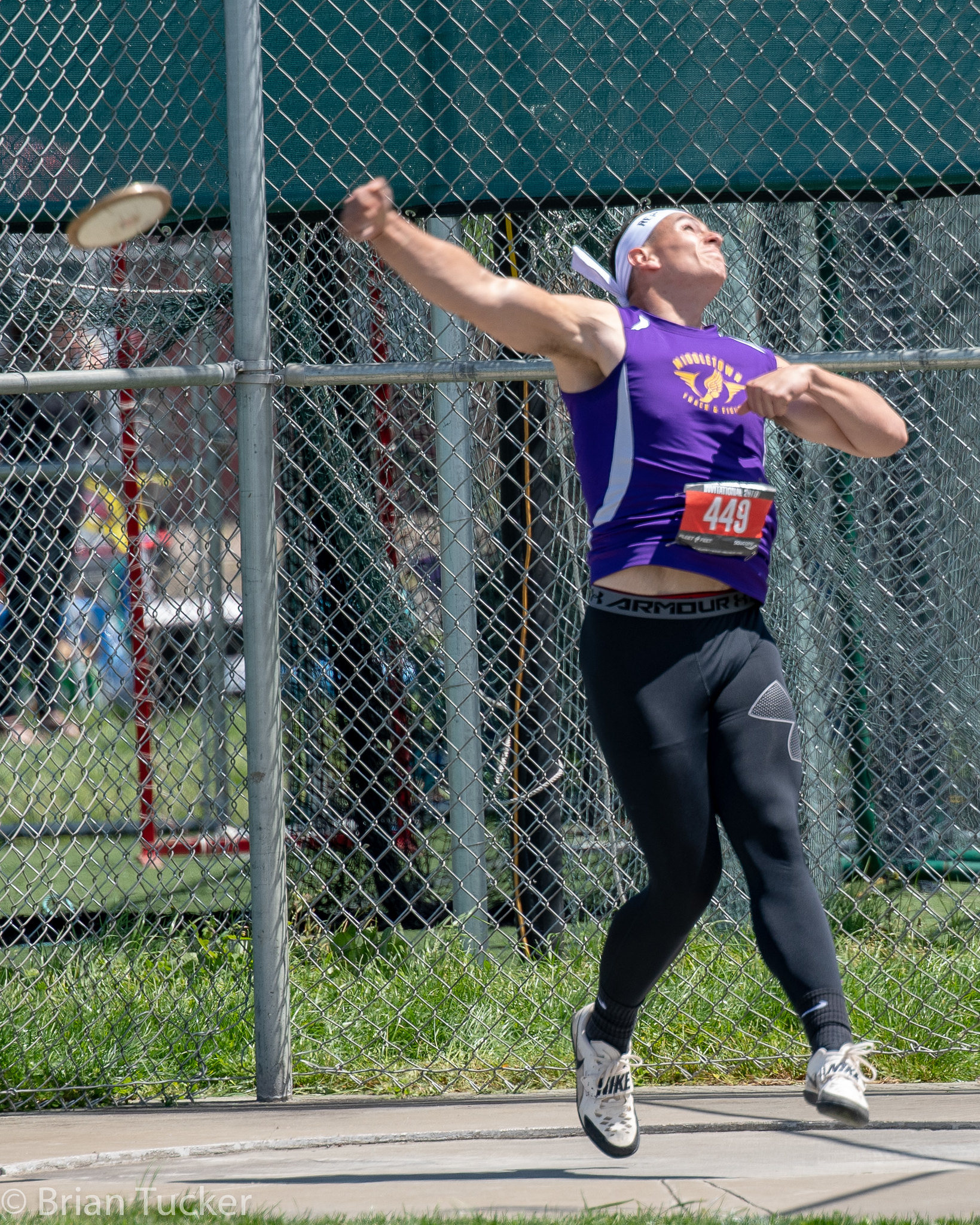 Athlete prepares for pole vault on a track with others watching.