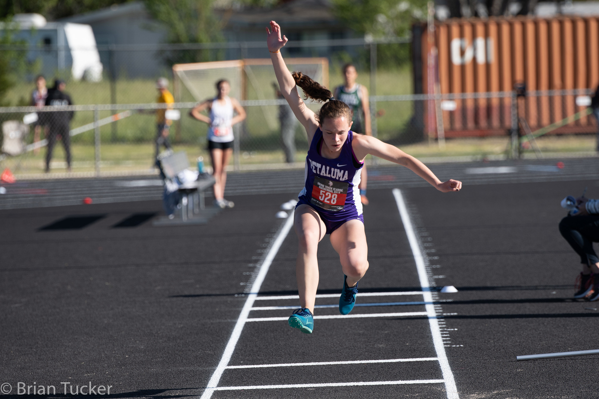 Athlete prepares for pole vault on a track with others watching.