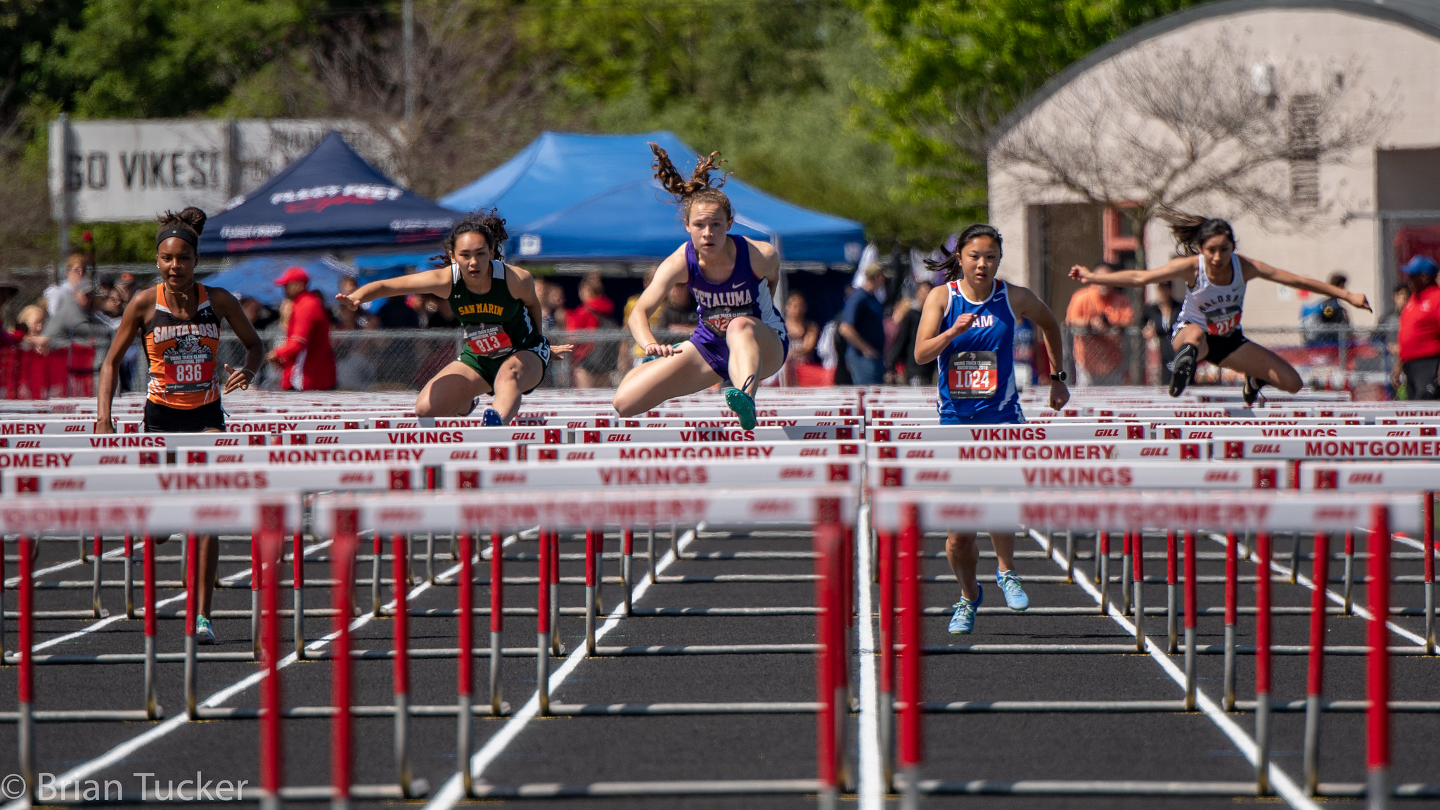 Athlete prepares for pole vault on a track with others watching.