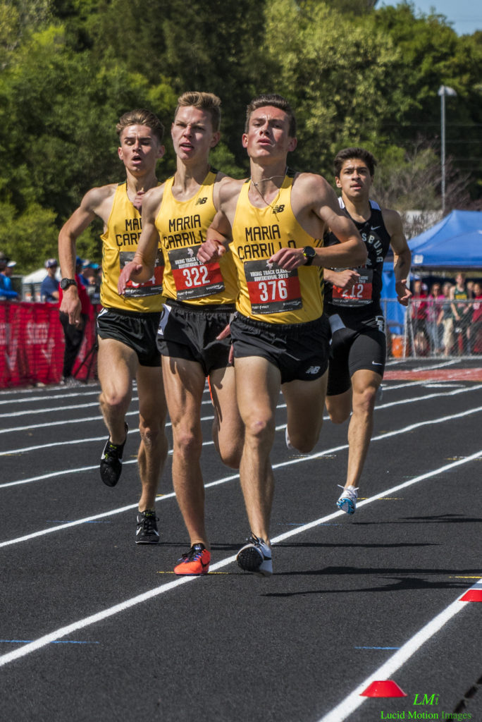 Athlete prepares for pole vault on a track with others watching.