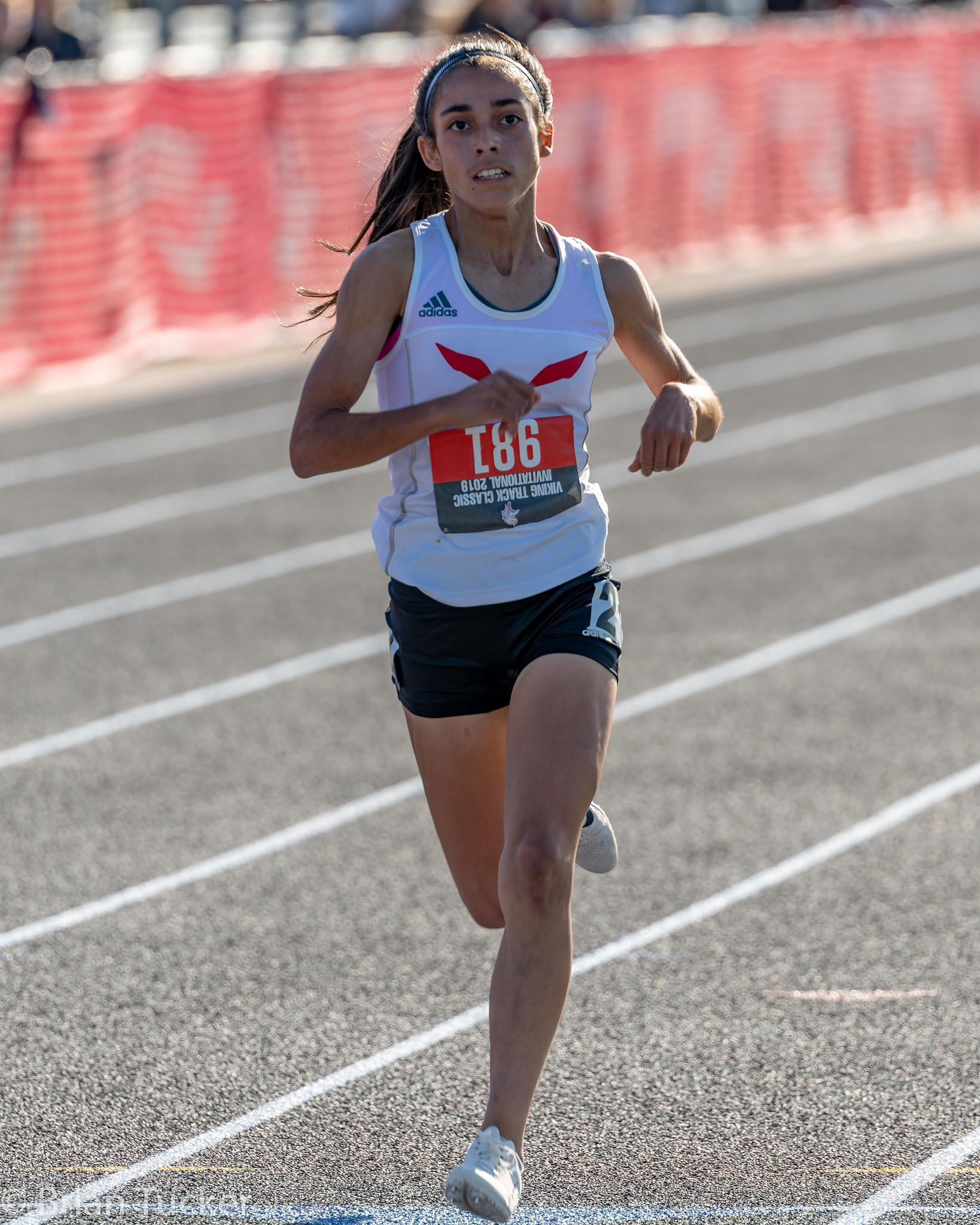 Athlete prepares for pole vault on a track with others watching.