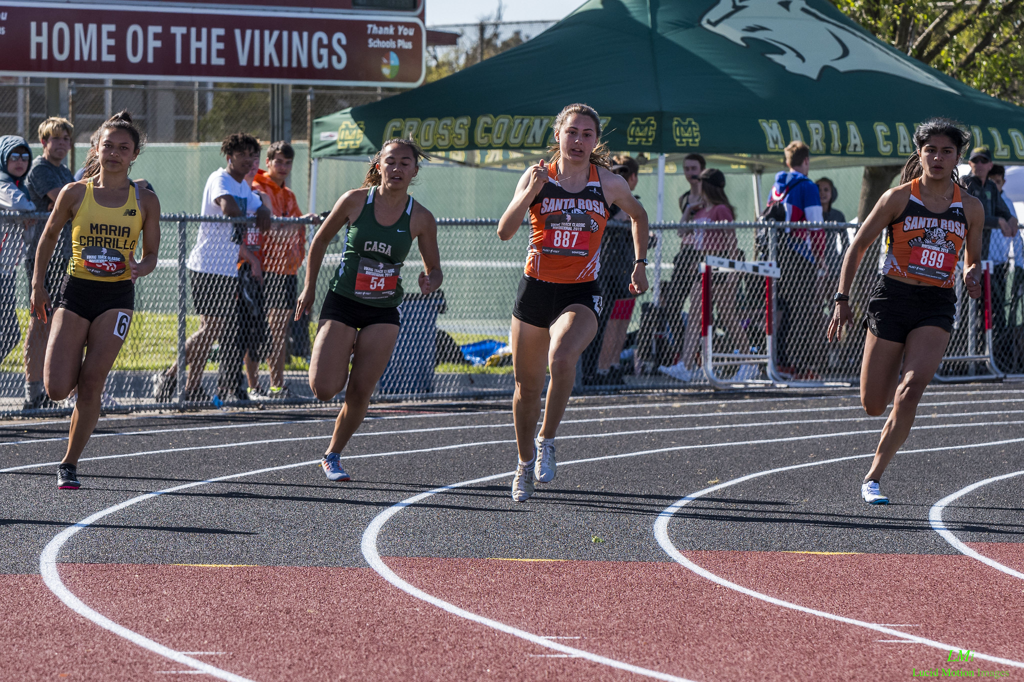 Athlete prepares for pole vault on a track with others watching.