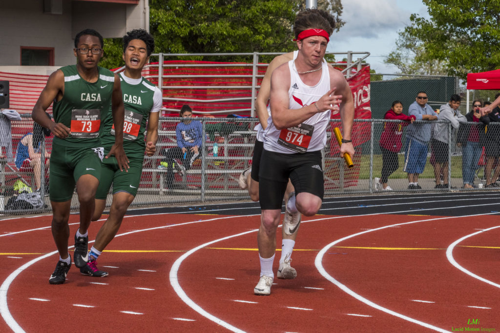 Athlete prepares for pole vault on a track with others watching.