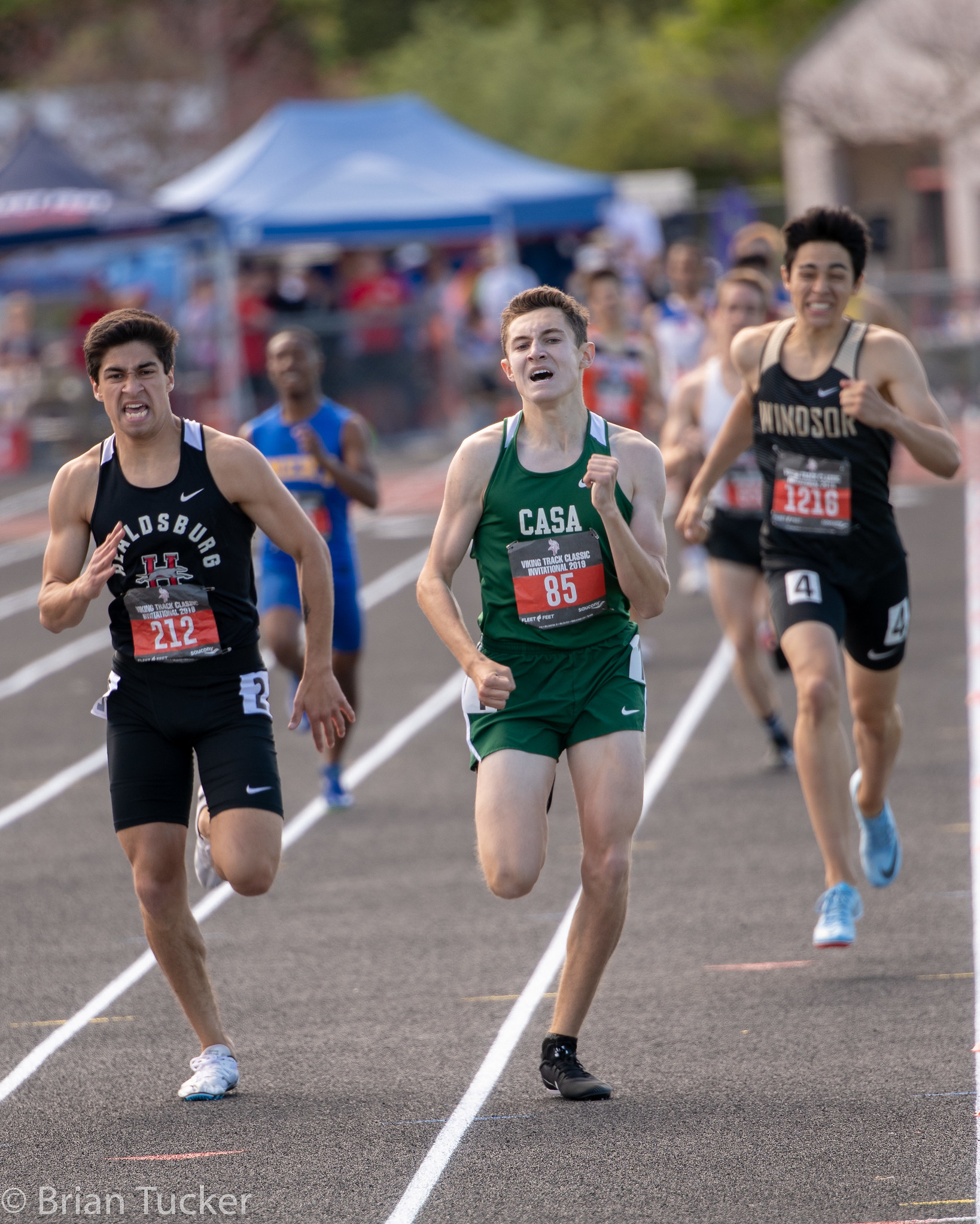 Athlete prepares for pole vault on a track with others watching.