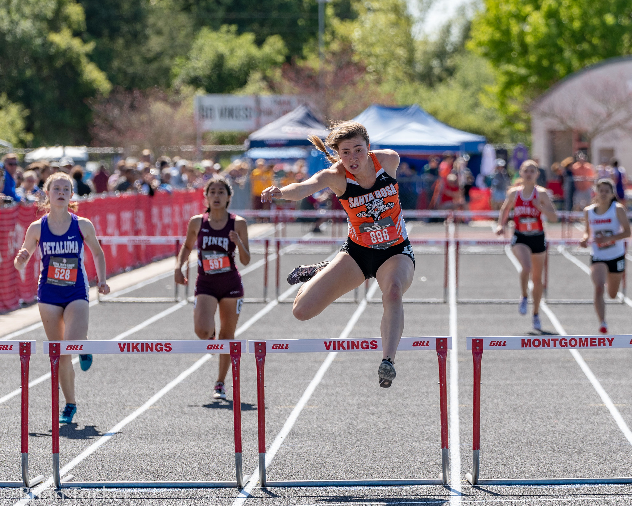 Athlete prepares for pole vault on a track with others watching.