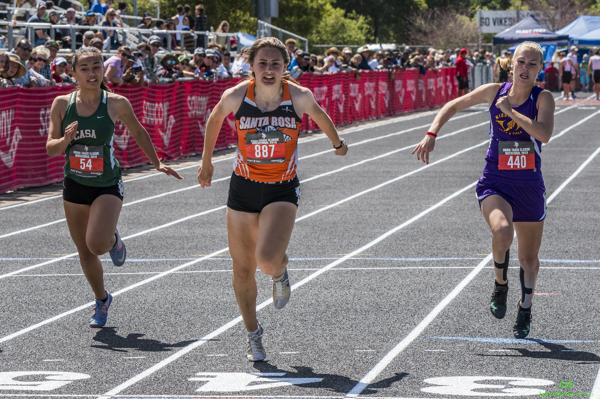 Athlete prepares for pole vault on a track with others watching.