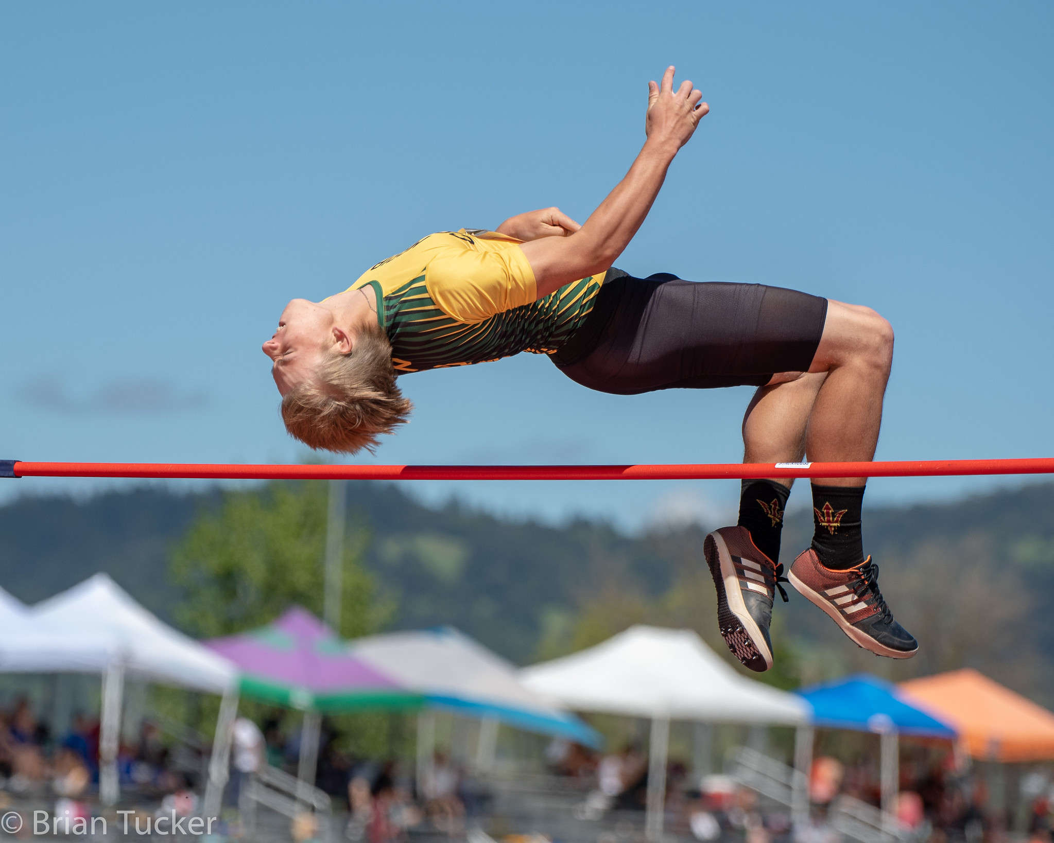 Athlete prepares for pole vault on a track with others watching.