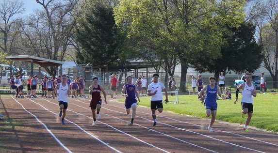 Athlete prepares for pole vault on a track with others watching.