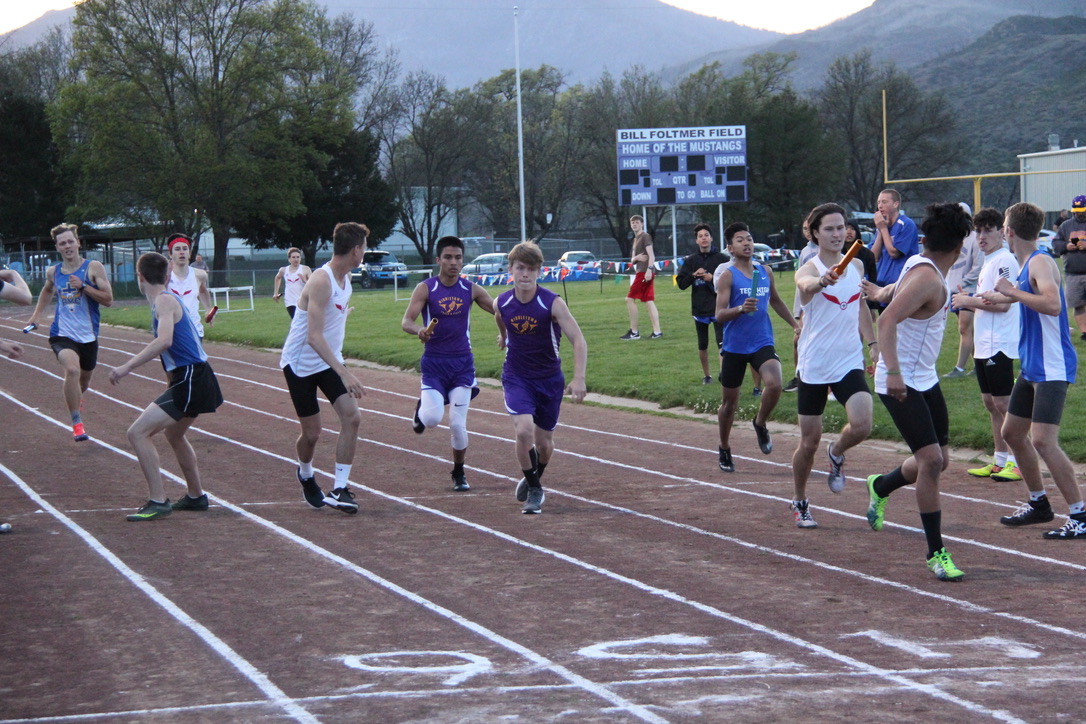 Athlete prepares for pole vault on a track with others watching.