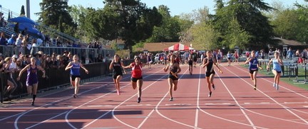 Athlete prepares for pole vault on a track with others watching.