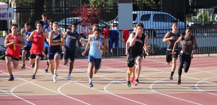 Athlete prepares for pole vault on a track with others watching.