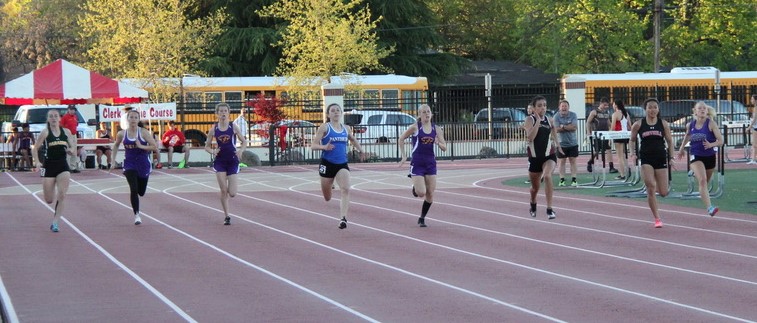 Athlete prepares for pole vault on a track with others watching.