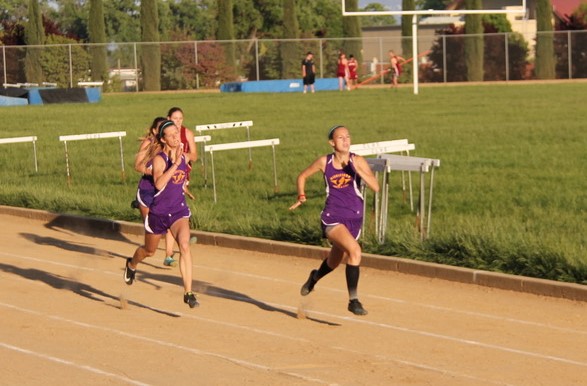 Athlete prepares for pole vault on a track with others watching.