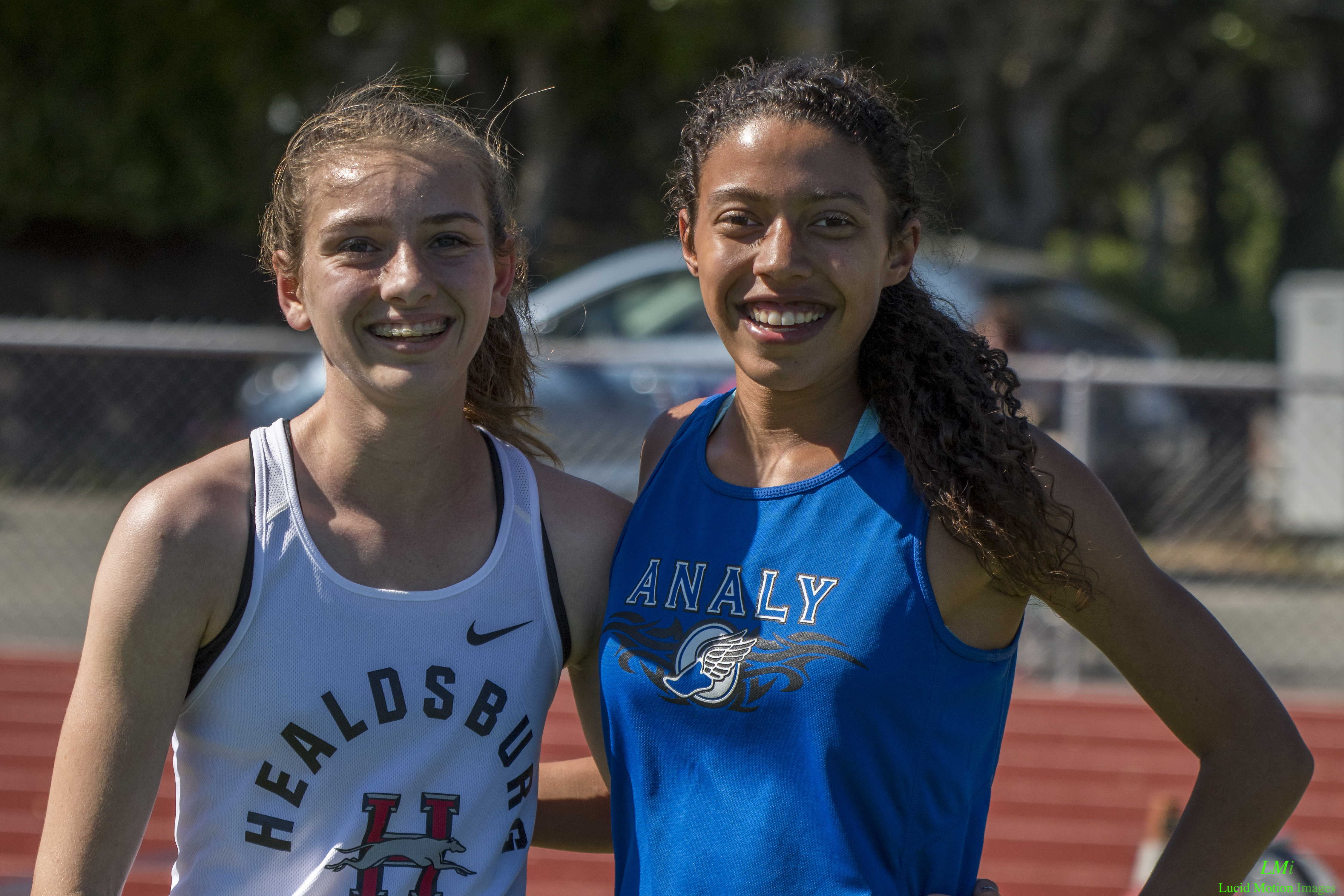 Athlete prepares for pole vault on a track with others watching.