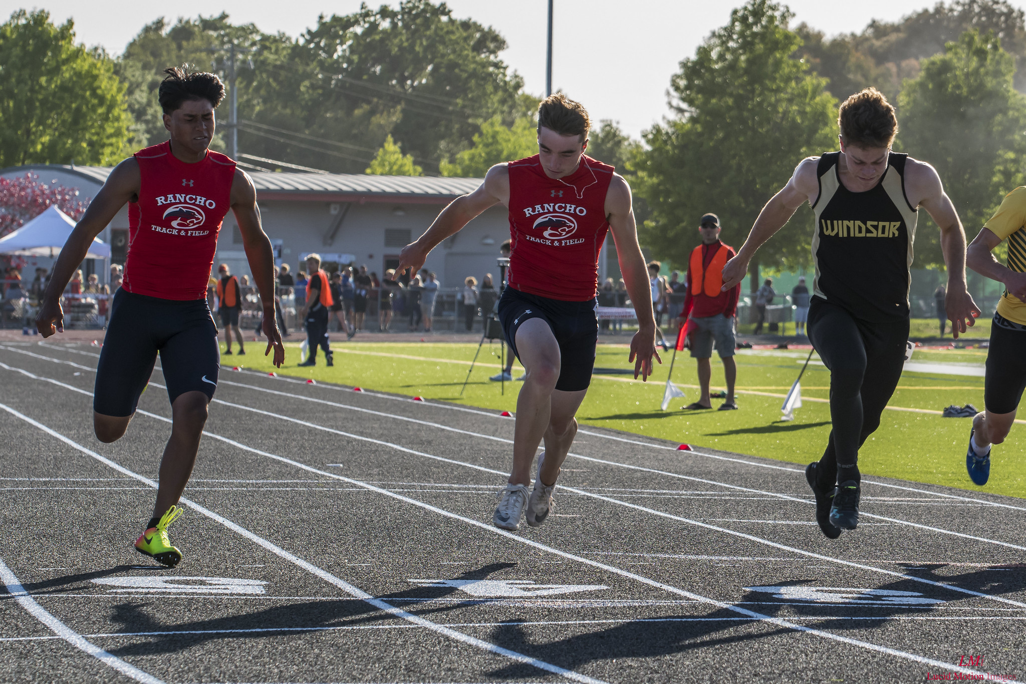 Athlete prepares for pole vault on a track with others watching.