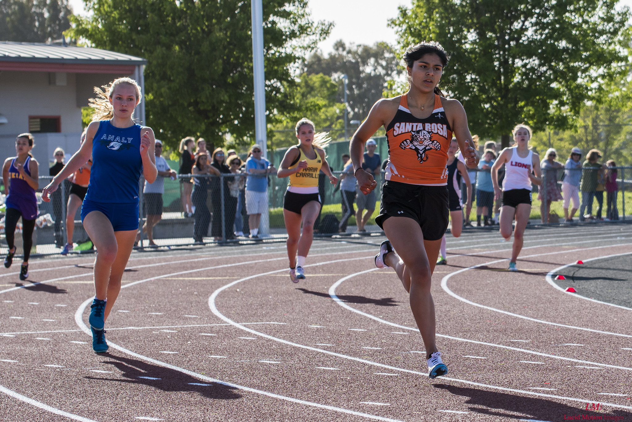Athlete prepares for pole vault on a track with others watching.