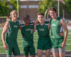 Athlete prepares for pole vault on a track with others watching.
