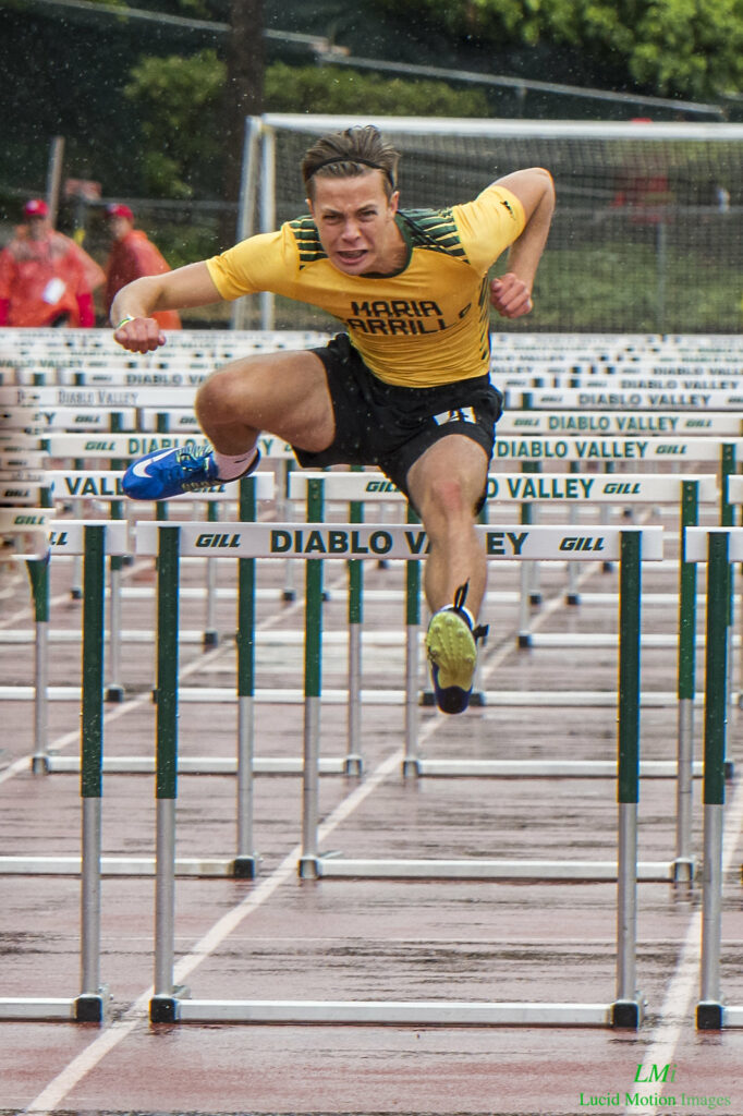 Athlete prepares for pole vault on a track with others watching.