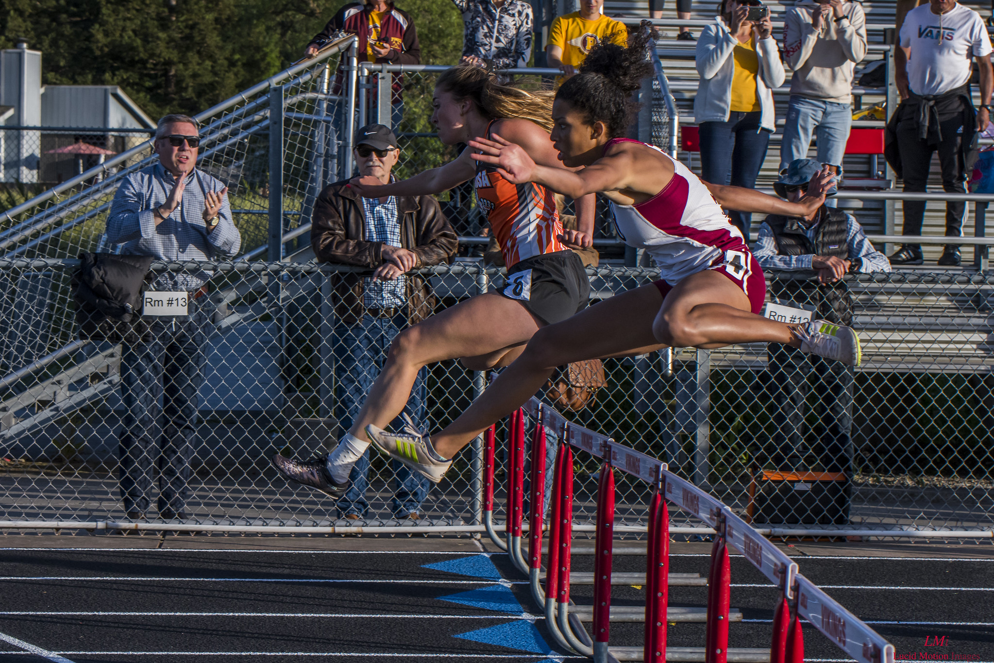 Athlete prepares for pole vault on a track with others watching.