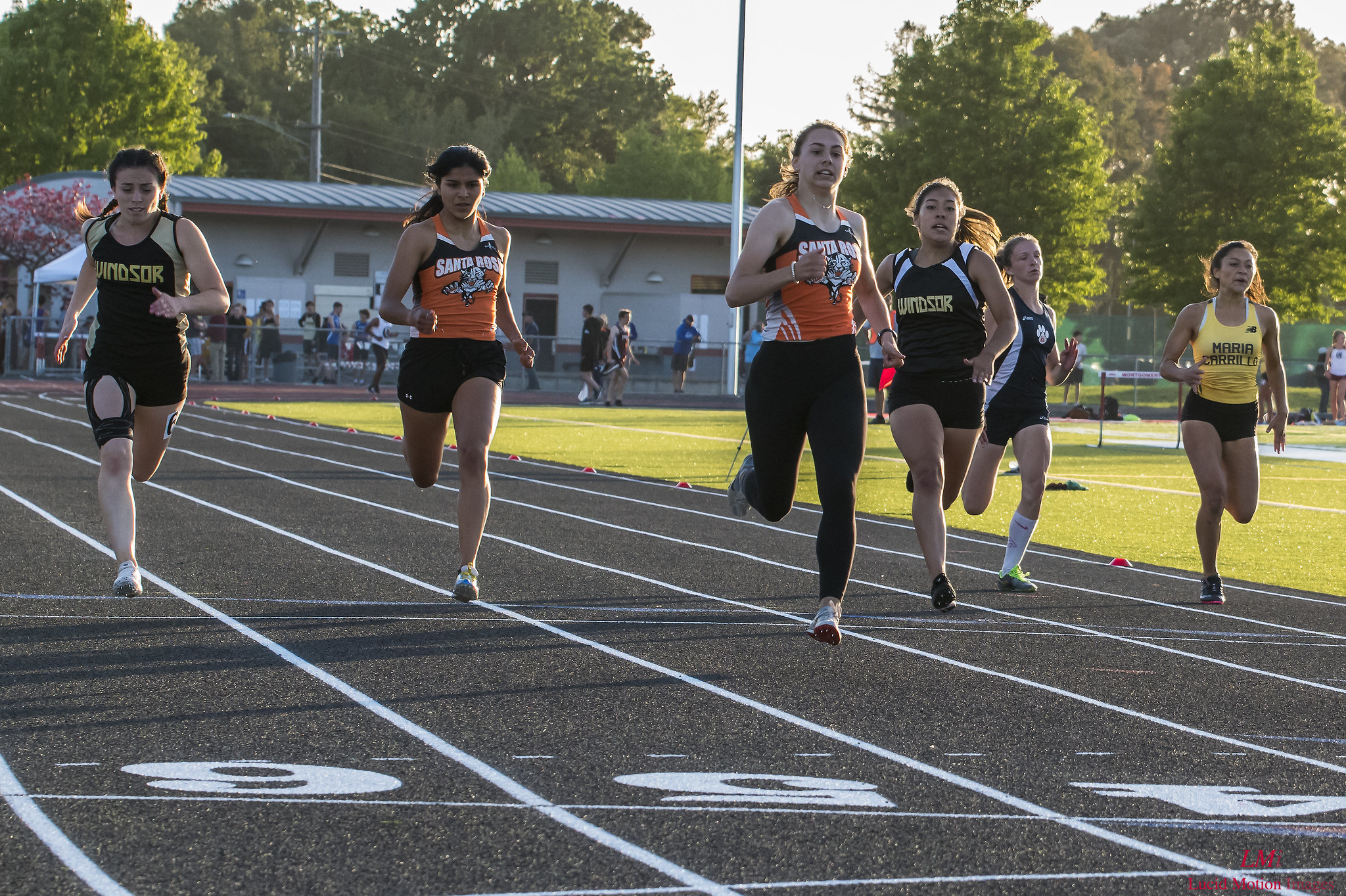 Athlete prepares for pole vault on a track with others watching.