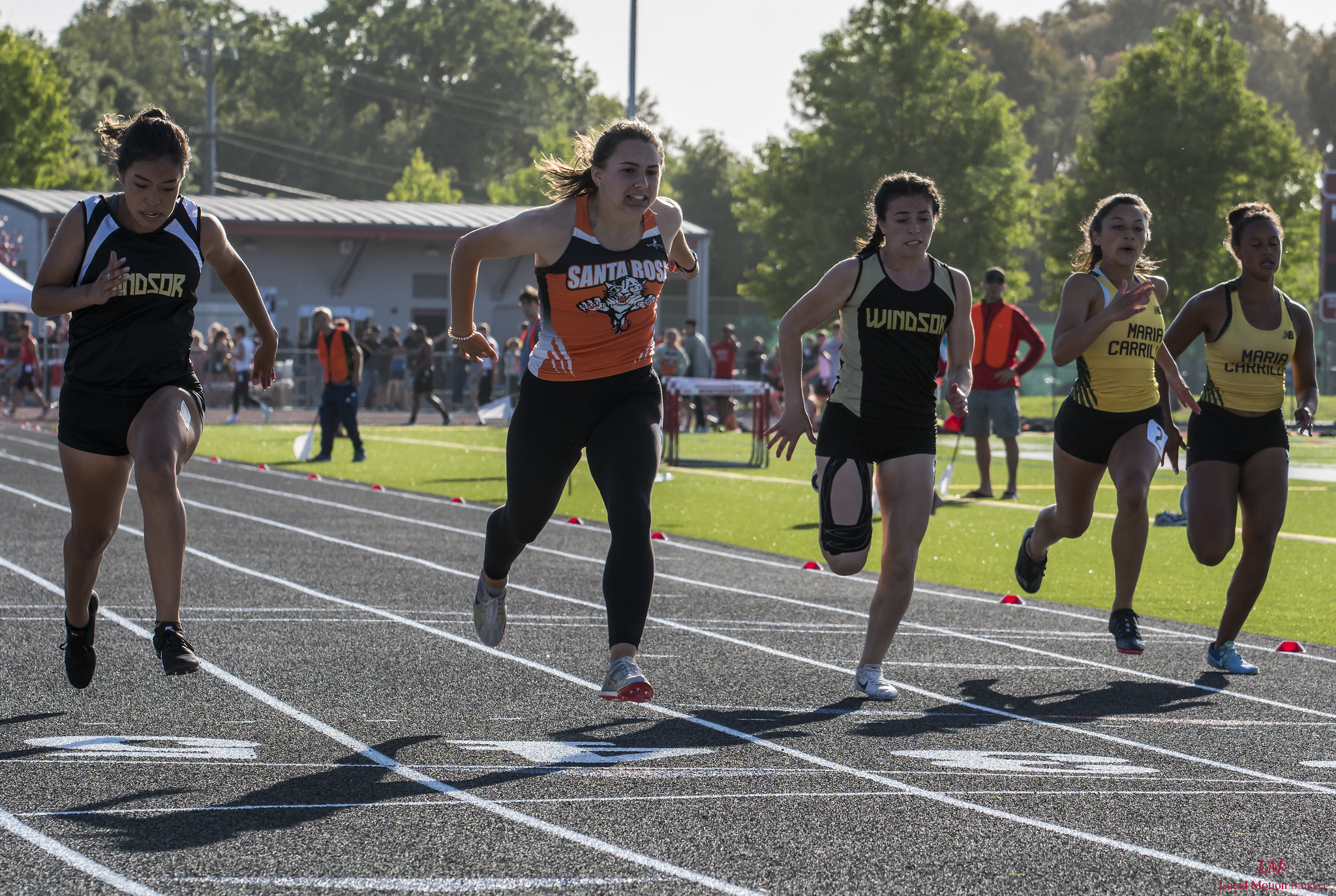Athlete prepares for pole vault on a track with others watching.