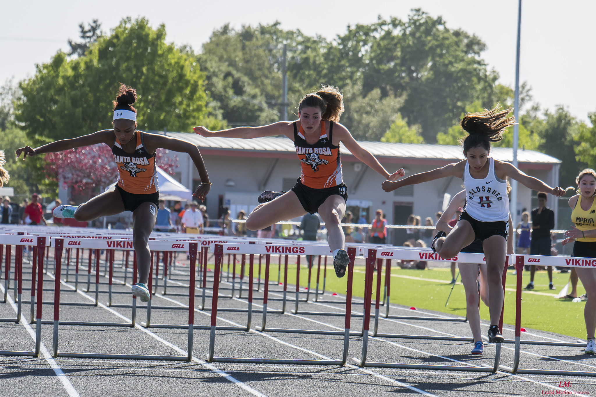 Athlete prepares for pole vault on a track with others watching.